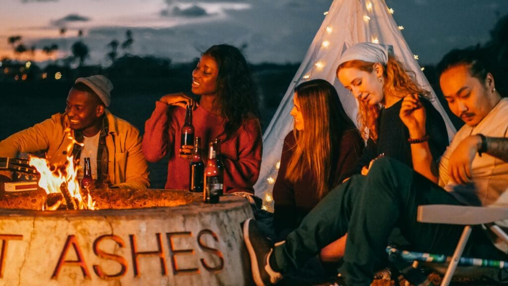 Group of friends sitting around a fire pit at night.