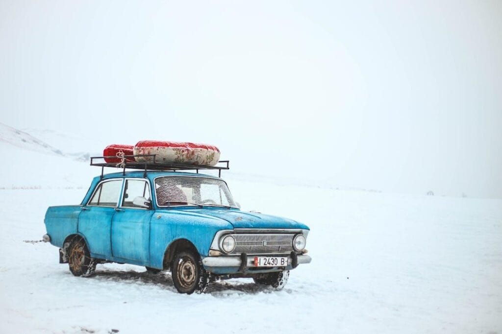 Blue sedan on snow during daytime
